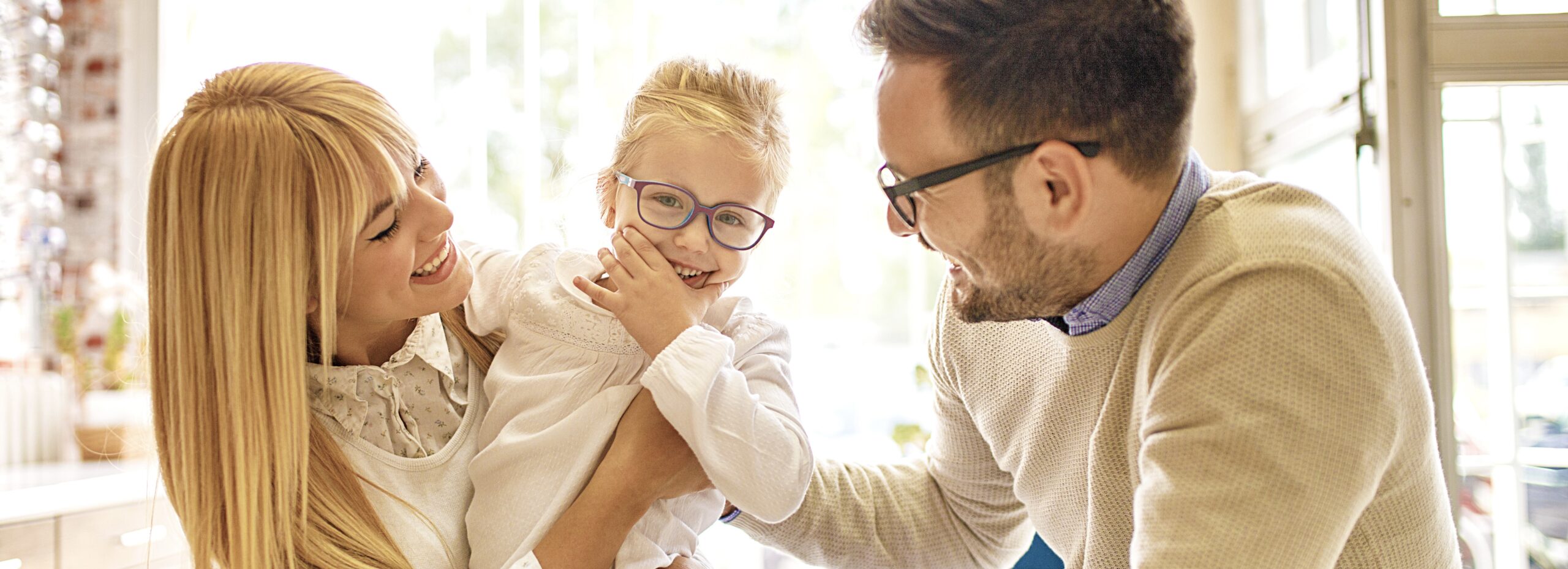 Happy family choosing glasses in optics store.