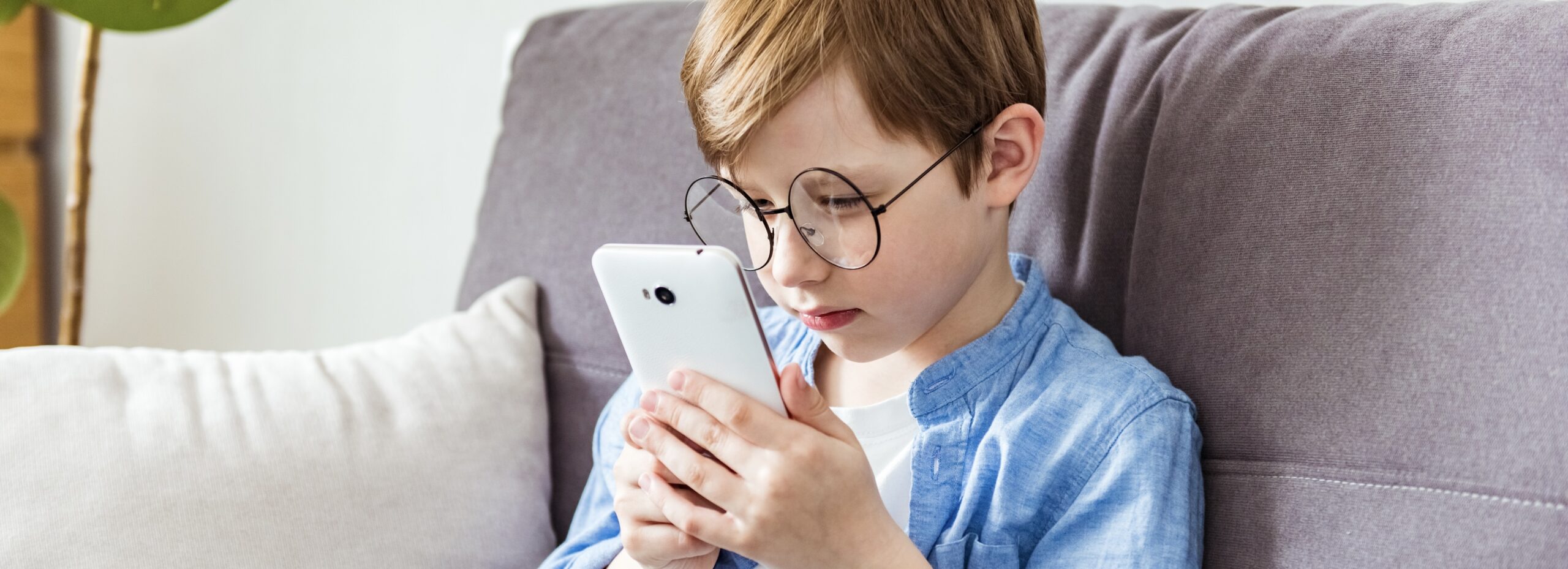Child looking close to his cellphone, screen time myopia causes