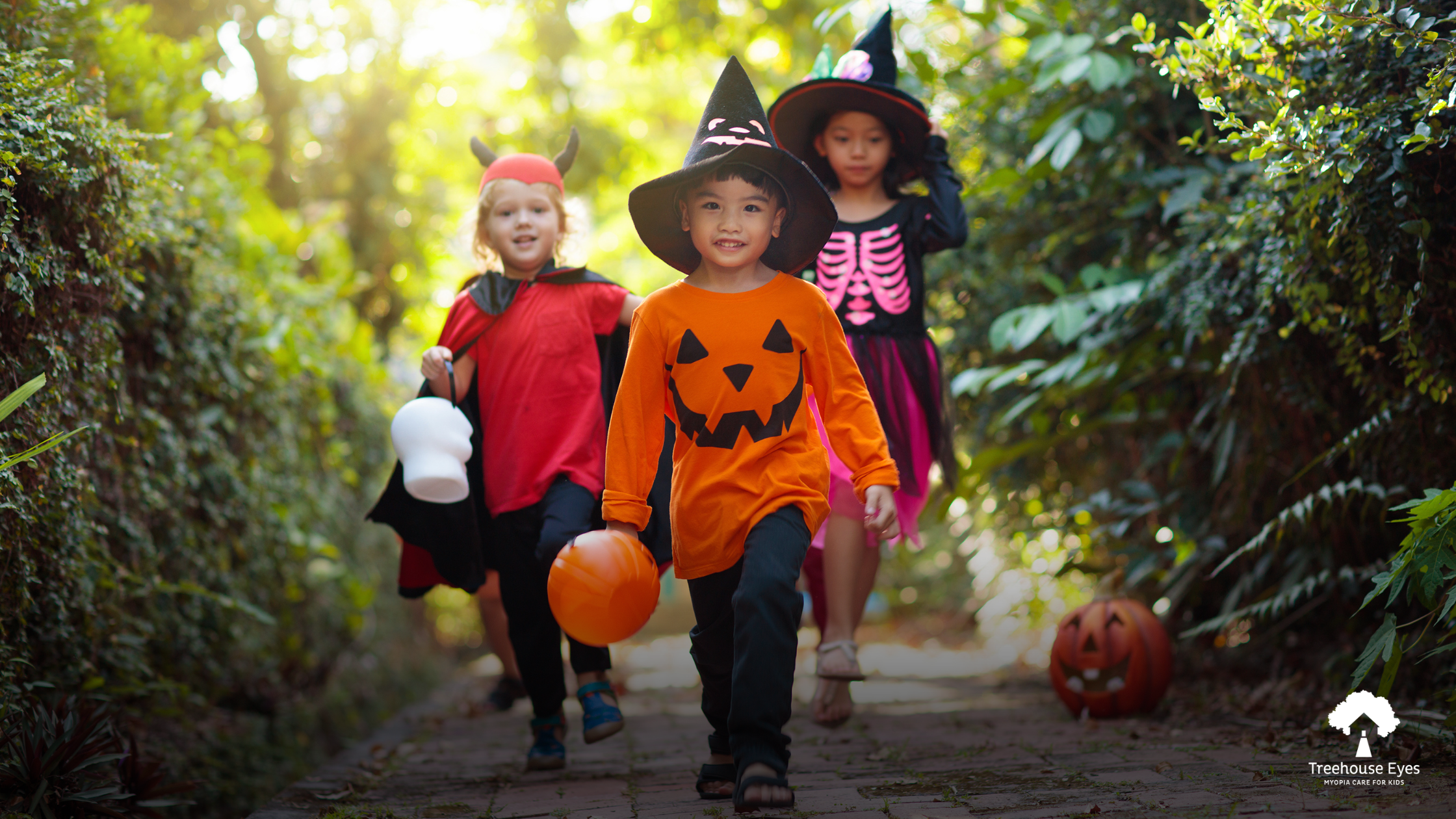 Three kids in halloween costumes strolling outside with halloween candy