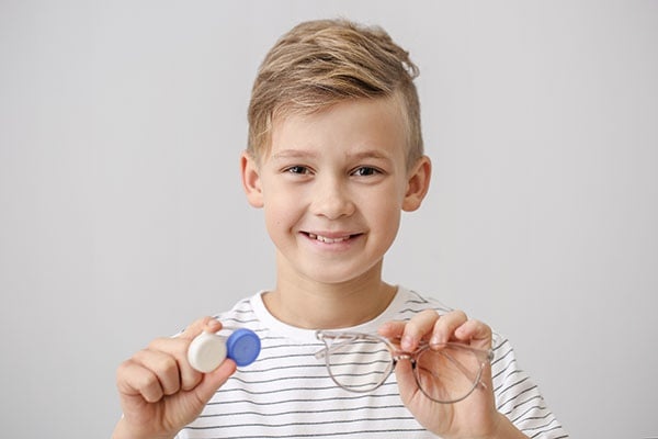 Myopia treatment for children at Treehouse Eyes in Winfield IL. Myopia control - boy holding glasses and contact lens case