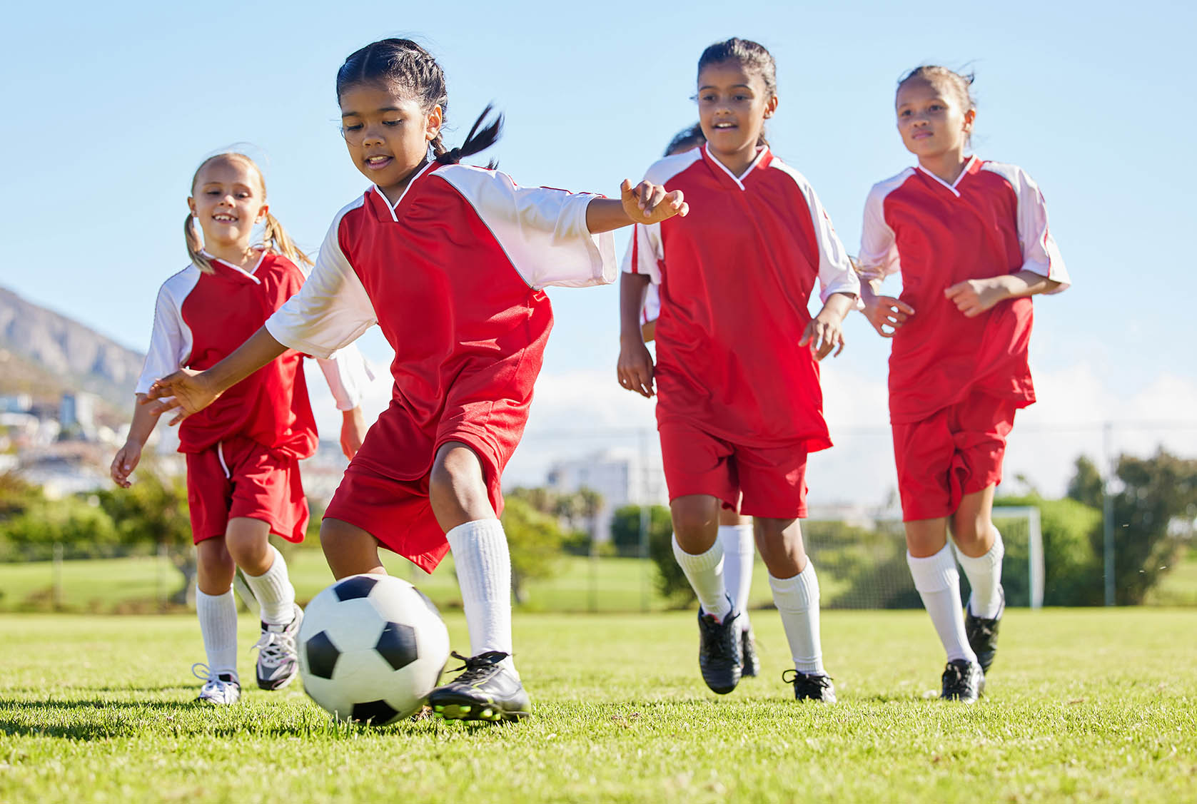Soccer, ball or sports and a girl team training or playing together on a field for practice. Fitness, football and grass with kids running or dribbling on a pitch for competition or exercise.